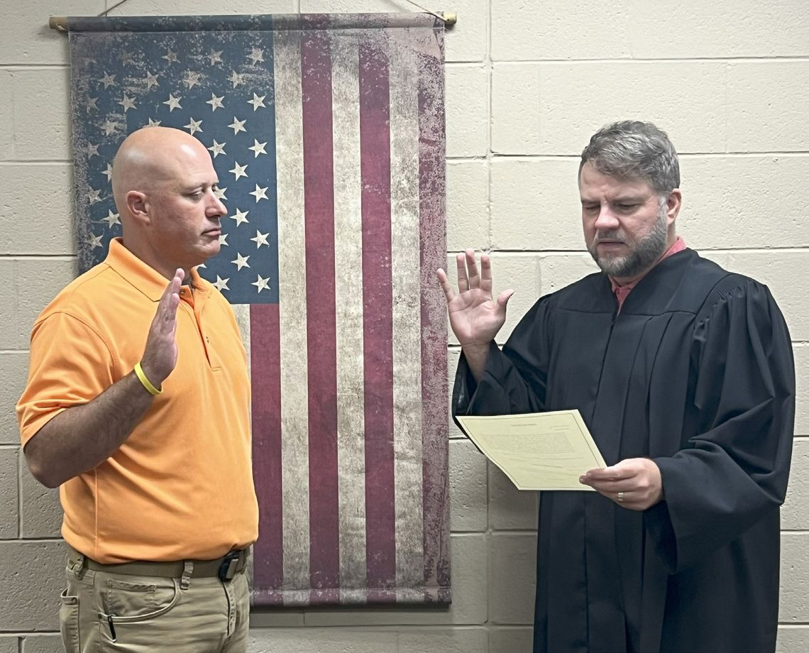 Newly appointed Atoka County Assessor Trey Harbin (left) is administered the oath of office by Judge Preston Harbuck following the Commissioner Meeting on Monday